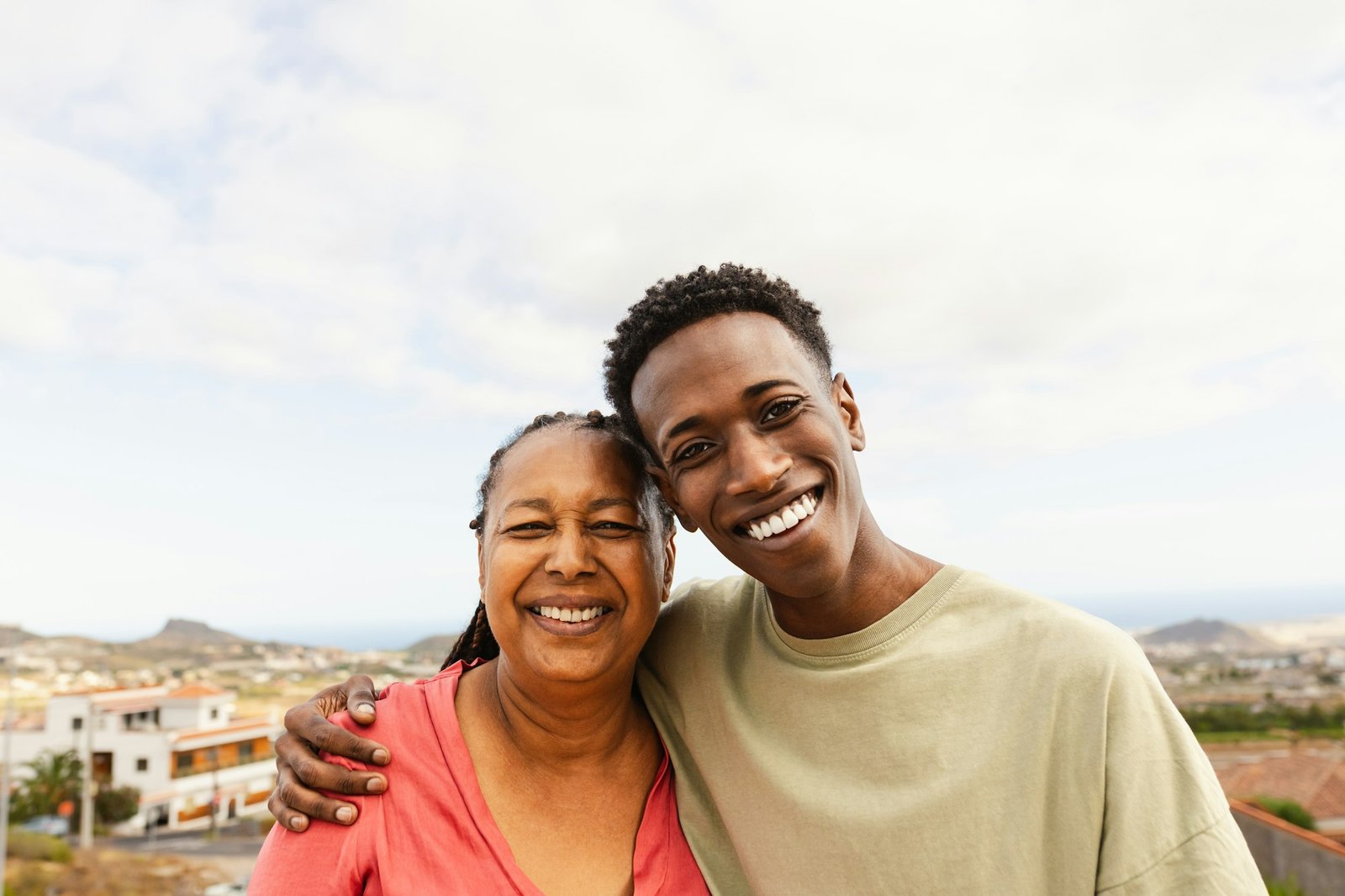 Happy African grandson hugging her grandmother at house rooftop